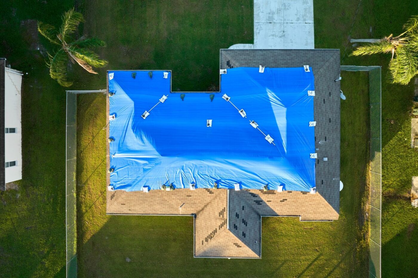 Hurricane Ian damaged house rooftop covered with protective plastic tarp against rain